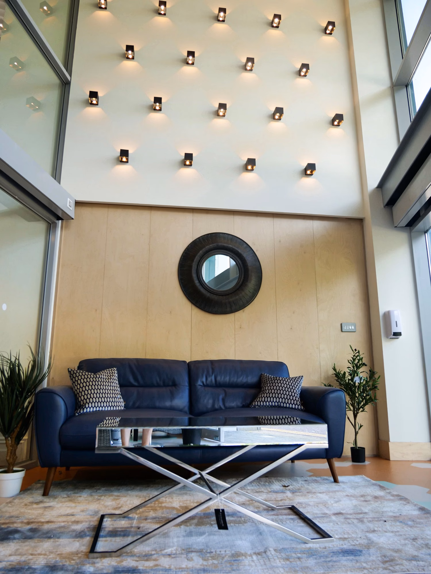 Mirrored coffee table placed in front of a blue sofa in a showroom setting